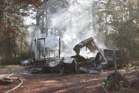 Remnants of a structure fire at 1531 Dunn-Worley Road smolder as Elbert County firemen walk around the structure on Thursday, March 12. The fire, listed as a “structure fire/arson” in the incident report from the Elbert County Sheriff’s Office, occurred at 9:22 a.m.  The Georgia Fire Marshal’s office said an Elbert County woman has been charged with causing the fire. (Photo by Scoggins).