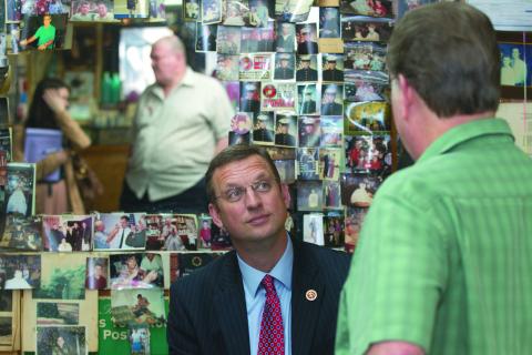 Doug Collins, shown in an Elberton Star file photo talking with Anderson Barber Shop owner Doug Anderson, talked to members of the Elbert County Chamber of Commerce in a conference call last week. (Photo by Best)