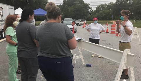 Patrick Reilly (right), who has coordinated free COVID-19 tests in Elberton for the past three weeks, briefs staffers prior to testing Monday morning as cars line up for testing. (Photo by Jones)