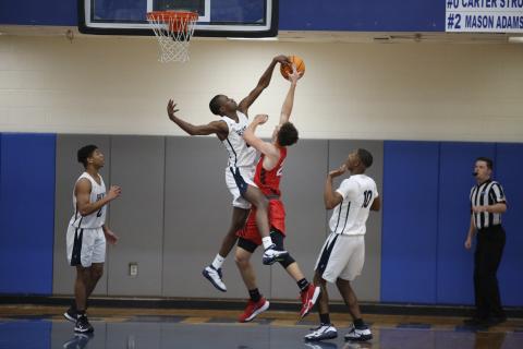 Sophomore Trustin Allen (left) and junior Jamil Burton (right) watch as senior Korbin Eberhardt (center) blocks a layup from a Rabun County Wildcat during the Devils’ competition against Rabun County during the Region 8-AA Tournament at Banks County Saturday, Feb. 13. (Photo by Scoggins) 