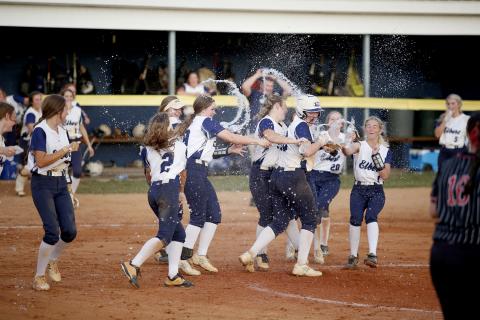 Lady Devil Lilly Ray (third from right) is rushed by a swarm of Lady Devil teammates with bottles of water after she singled on a hard ground ball and teammate Ava Lunsford scored the final run for the Lady Devils during the Sept. 9 10-2 region victory over Rabun County. (Photo by Scoggins)