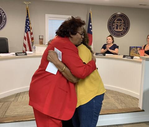 Bowman city council member Henrietta Williams hugs Betty Harper from the Economic Justice Coalition/Elbert County Community Friends after Williams presented Harper a $15,000 check after the council approved the group’s request for funding from ARPA funds during the May meeting. (Photo by Scoggins)  