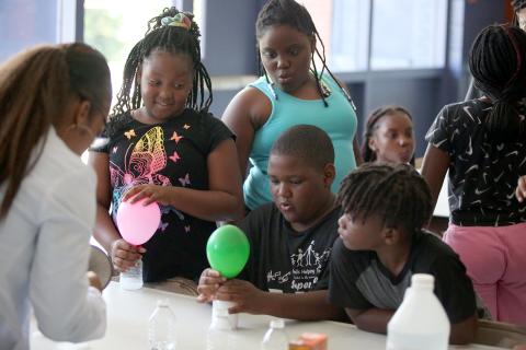 Children in the Elbert County Community Friends’ summer activities program received a lesson in chemistry from Elbert County’s own chemist, Pamela Brown, Monday, June 20 at the Mill Street Gym. Brown performed an experiment that allowed children to blow up balloons by having baking soda in the balloons mix with vinegar in a recycled water bottle. Elbert County Community Friends hosted a day of youth activities at the gym as part of the weekend’s Juneteenth celebration. (Photo by Scoggins) 