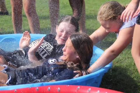 Lady Devils softball camper Karson McKeller (right) helps hold down Lady Devils Lilly Ray (back) and Kamryn Webb (front) in the polar plunge challenge during the Lady Devils’ youth softball camp July 11 through July 13.