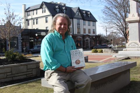Author Clay Ouzts sits in front of the Samuel Elbert hotel with his book, "Samuel Elbert and the Age of Revolution in Georgia," written about the hotel and county's namesake, Samuel Elbert. (Photo by Wells)