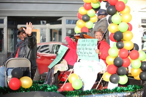 Parade float riders from Vance Creek Baptist Church wave while others hold up signs with quotes from Martin Luther King Jr. (MLK) during the annual MLK. parade Jan. 15. See more photos from the parade and annual Ecumenical Banquet on page 12. (Photo by Wells) 