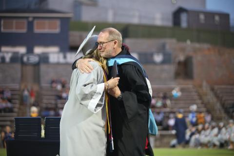 Former superintendent Jon Jarvis hugs his niece, Emma Grace Jarvis, after handing her her diploma as the valedictorian for the Elbert County Comprehensive High School Class of 2023. The May 26 graduation was Jarvis’ last event as superintendent. (Photo by Scoggins)