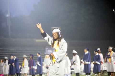 ECCHS senior De'Asia Kinsey waves to the crowd as she proudly displays her diploma during the May 24 graduation ceremonies in the Granite Bowl.  (Photo by Wells)