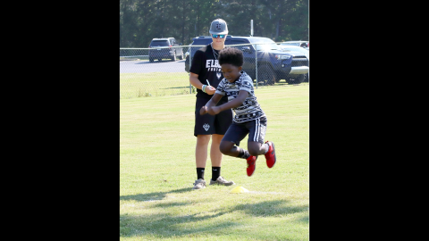Elbert county fourth grader Lajarvis Heard Jr. propels himself through the air as rising sophomore Braydon Lyon of the ECCHS football program records his jump length.  Lajarvis was one of a couple hundred young people taking part in this year's Friends Helping Friends Club, Inc. Fun Football Day. (Photo by Weeks)