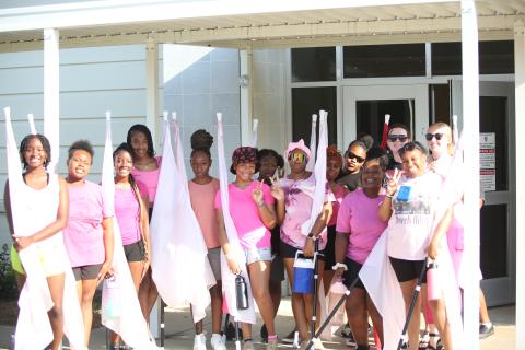 (L-R) Chastity DeJesus, Destiny Patman, Cheslie DeJesus, Ciara Rucker, JerMiriya Perrin, Taniya White, Kemiya Burton, Maurissa Heard, Zaniya Huff, University of Georgia Instructor Addison Kiser, Jimora Brightwell and Color Guard Coach Camilla Long pose for a picture outside the multipurpose room during a break in color guard practice. (Photo by Wells)