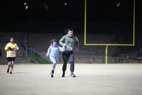 A man and girl run in the Twilight Stroll by the Granite Bowl.
