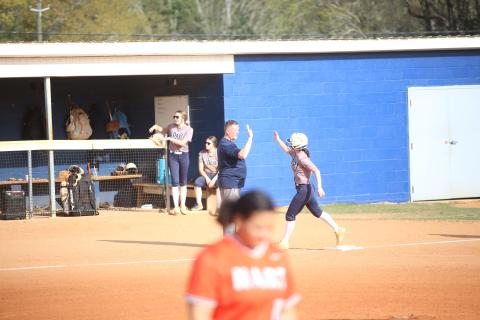 Head coach Josh Jones high-fives Bellamy Nash (5) as she rounds third base following a home run. (Photo by Bo Underwood)