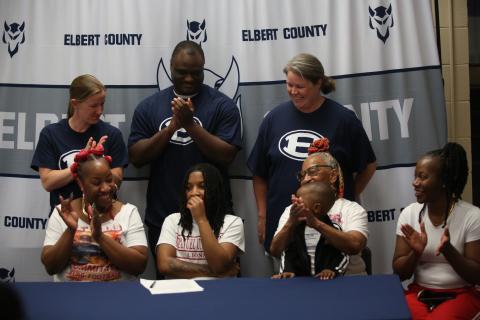 Zoe Evans (bottom row, second from left) signs her letter of intent to play flag football at Emmanuel University. Evans was joined by (bottom row from right:) godmother Tanya Allen, brother Ezequiel Calhoun, mother Davasia McLendon and grandmother Debbie Carpenter. (top row from right:) ECCHS flag football head coach Ashley Bryant and assistant coaches A.J. German and Sarah Navarro.