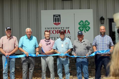 (L-R) Commissioners Mike Scoggins, David Hunt, commission chair Lee Vaughn, Commissioners Casey Freeman, Chris Alexander and county manager Allen Hulme prepare to cut the ribbon during a ceremony celebrating the grand opening of the county's new 4-H facility. (Photo by Bo Underwood)