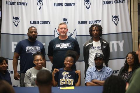 Kaylen Rucker (bottom row, middle) smiles after signing her letter of intent with Columbia International University. Rucker was joined at the table by father Clinton Rucker and mother Kristen P. Simpson, grandmother Gloria Partlow, grandmother Shelia Allen, aunt Karen Partlow Burton, Lady Devils head coach Josh Jones and assistants Donald Bolton and James Allen. (Photo by Bo Underwood)