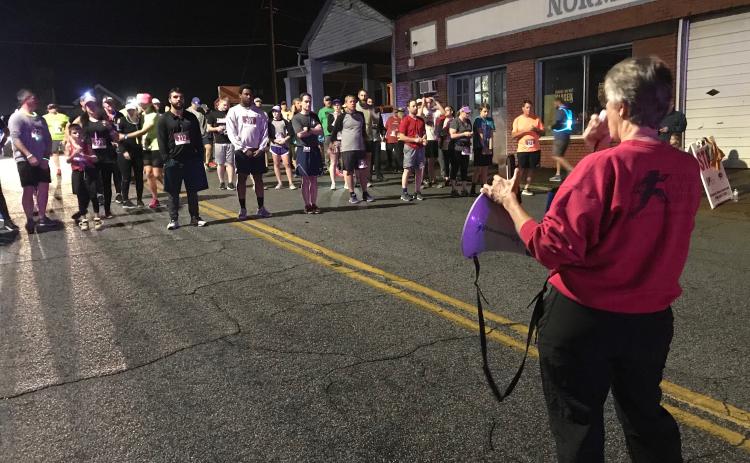 Carol Baker, whose company (Classic Race Services) times runners for the Twilight Stroll, gives instructions to runners before the 5K start. (Photo by Jones)