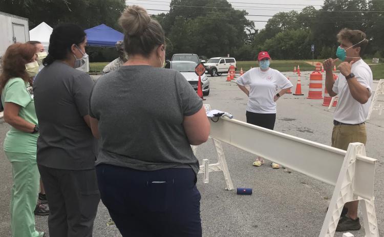 Patrick Reilly (right), who has coordinated free COVID-19 tests in Elberton for the past three weeks, briefs staffers prior to testing Monday morning as cars line up for testing. (Photo by Jones)