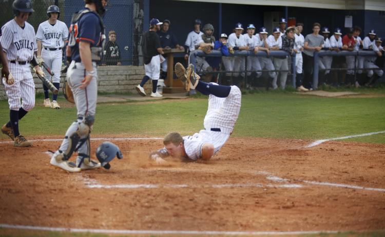 Sophomore Skylar Bray eats dirt with his helmet flying off as he slides into home in the bottom of the first during the Diamond Devils’ competition against Habersham Central Tuesday, March 23. (Photo by Scoggins)