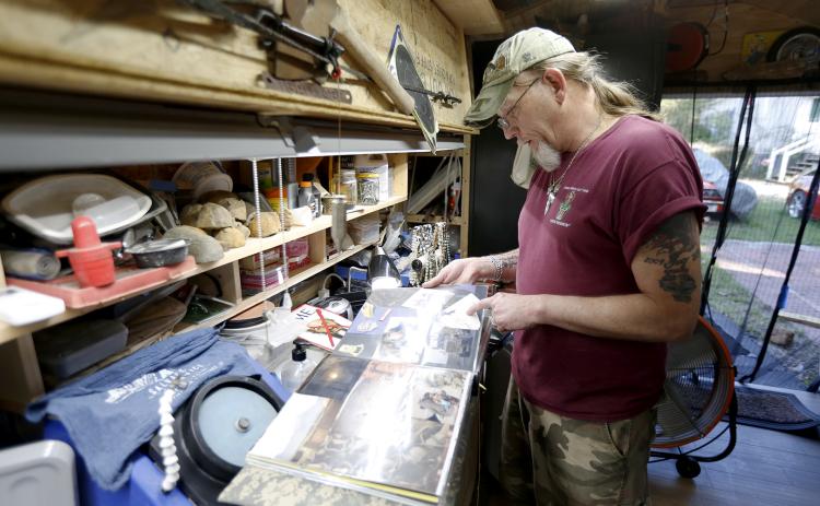 Allen Cartledge looks through a scrapbook from one of his deployments in a shed he has turned into his workshop and “sanctuary” in his backyard. Cartledge was deployed in Iraq from 2009-2010 and in Afghanistan from 2013-2014. (Photo by Scoggins)