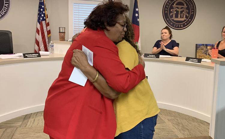 Bowman city council member Henrietta Williams hugs Betty Harper from the Economic Justice Coalition/Elbert County Community Friends after Williams presented Harper a $15,000 check after the council approved the group’s request for funding from ARPA funds during the May meeting. (Photo by Scoggins)