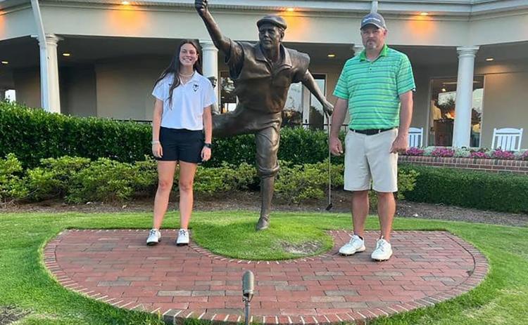 Lady Devil golfer (left) and Devils Head Coach Larry Kesler (right) stand next to a statue of Payne Stewart, the winner of the U.S. Open at Pinehurst No. 2 golf course in 1999.