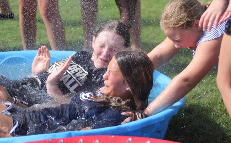 Lady Devils softball camper Karson McKeller (right) helps hold down Lady Devils Lilly Ray (back) and Kamryn Webb (front) in the polar plunge challenge during the Lady Devils’ youth softball camp July 11 through July 13.