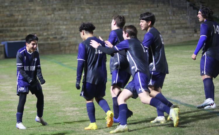 A group of Blue Devils celebrate with teammate Pablo Medellin (left) following the team’s 4-3 overtime win over Rabun County March 14 in the Granite Bowl. The win put the Devils in second place in the region. (Photo by Wells)