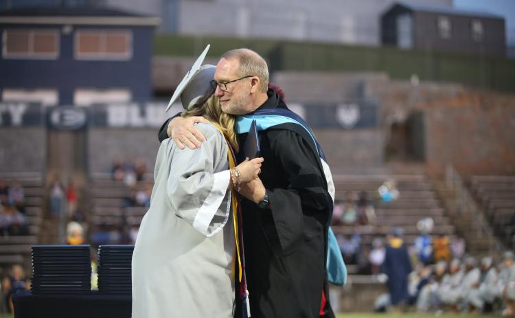 Former superintendent Jon Jarvis hugs his niece, Emma Grace Jarvis, after handing her her diploma as the valedictorian for the Elbert County Comprehensive High School Class of 2023. The May 26 graduation was Jarvis’ last event as superintendent. (Photo by Scoggins)