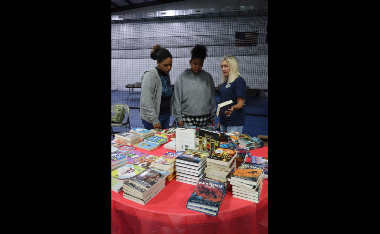 During the Pleasant Grove Baptist Back to School Bash Elbert County Comprehensive High School senior Nathalia Aquino and Elbert County Middle School eighth grader Nalleoi Aquino discuss book titles with Tanya Long, retired Director of Teaching and Learning for Elbert County Schools. (Photo by Weeks)