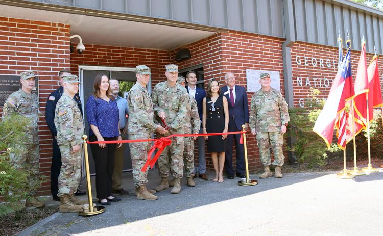Georgia Army National Guard members along with local city, county and state officials look on as Captain Elisha Campbell and Brigadier General Jason Fryman cut the ribbon signalling the re-opening of the local National Guard Armory. (Photo by Weeks)