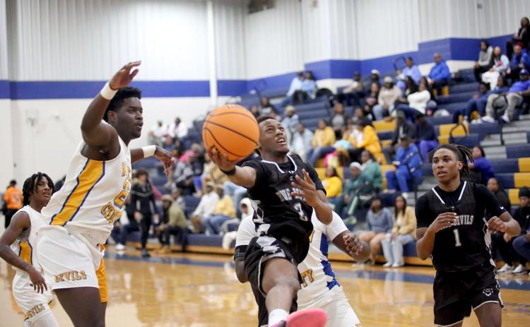 Jordan Morrison leaps as he lays the ball in with one hand in between a pair of Screaming Devil defenders during Elbert’s loss to Warren County Jan. 18. (Photo by Wells)