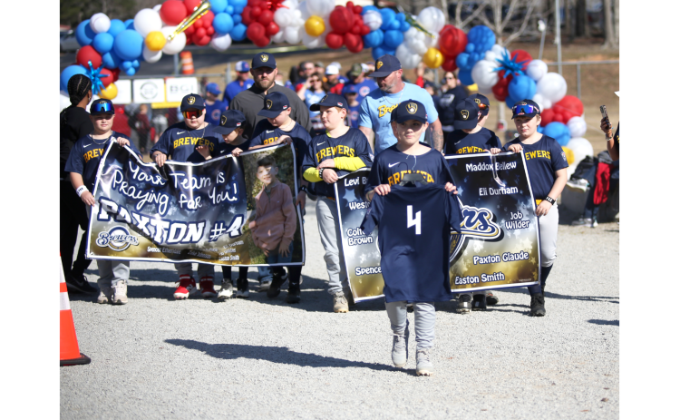 The Brewers carried a special sign in honor of their teammate, 9-year-old Paxton Glaude, who was recently seriously injured in a car accident. Carrying his #4 jersey is his cousin, Spencer Ethridge, who was also involved in the accident. (Photo by Wells)