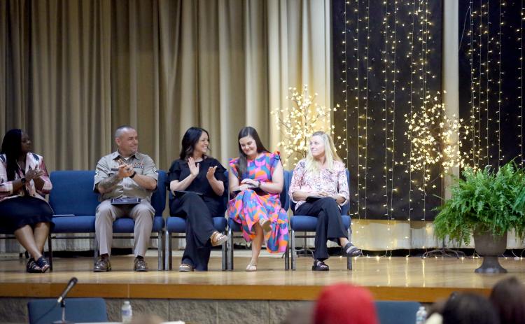 Elbert County Primary School first-grade teacher Meredith Lawson (second from right) learns that she was named district teacher of the year while SFC Daniel Ulrich (far left), Wendy Collier (second from left) and Tina Lunsford (far right) congratulate Lawson during the Elbert County Board of Education's May 19 regular meeting in the Elbert County Middle School auditorium. (Photo by Wells)