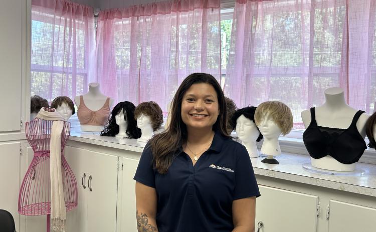 Jenny Jenkins, founder of Jenny's Boutique poses in front of some of the boutique's wig selection. (Photo by Mark Wells)