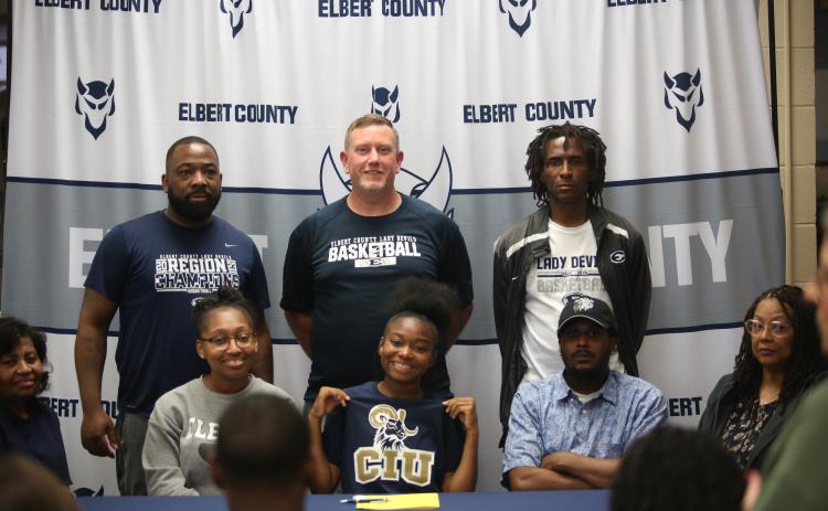 Kaylen Rucker (bottom row, middle) smiles after signing her letter of intent with Columbia International University. Rucker was joined at the table by father Clinton Rucker and mother Kristen P. Simpson, grandmother Gloria Partlow, grandmother Shelia Allen, aunt Karen Partlow Burton, Lady Devils head coach Josh Jones and assistants Donald Bolton and James Allen. (Photo by Bo Underwood)