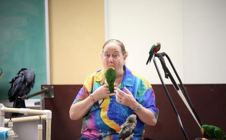 One of the many tricks Brenda Bean of Parrot Productions has perfected is putting one of her bird's full heads in her mouth. The trick was part of Tropical Birds with Bean and Bird at the Elbert County Public Library. (Photo by Bo Underwood)