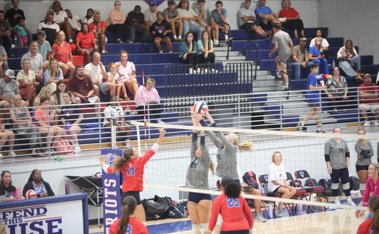 Elbert County volleyball players jump up to block the ball. (Photo by Bo Underwood)