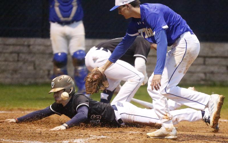 Blue Devil senior Brayden Eavenson scores as Tiger Nathan Durham (right) attempts to make a tag in the fifth inning of Elbert County’s 9-0 home-opening win over Washington-Wilkes Feb. 10 on Devils Field. (Photo by Cary Best)