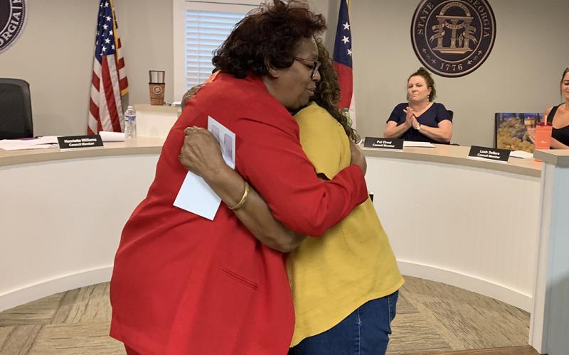 Bowman city council member Henrietta Williams hugs Betty Harper from the Economic Justice Coalition/Elbert County Community Friends after Williams presented Harper a $15,000 check after the council approved the group’s request for funding from ARPA funds during the May meeting. (Photo by Scoggins)  