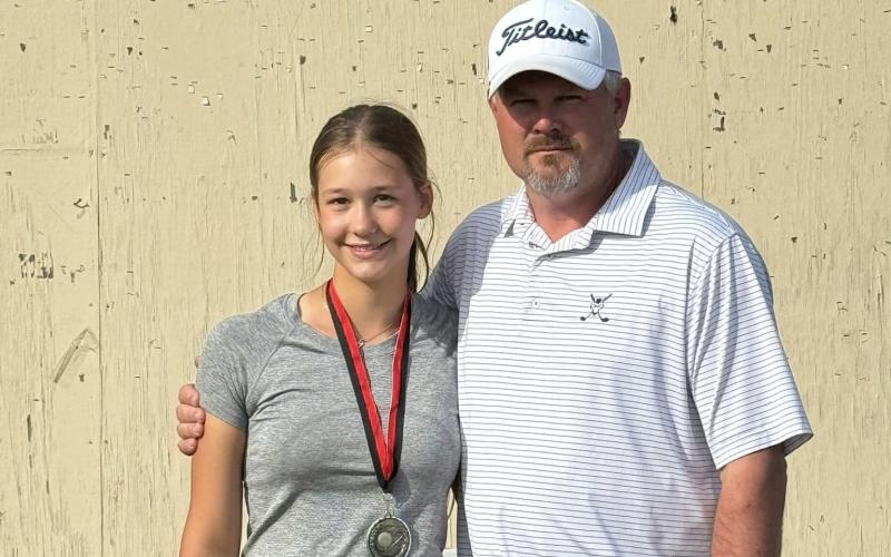 Lucy Johnson (left) and Head Coach Larry Kesler (right) pose after Johnson was awarded her second place medal after finishing second in the individual standings of the Cougar Invitational. (Photo courtesy of Kesler)