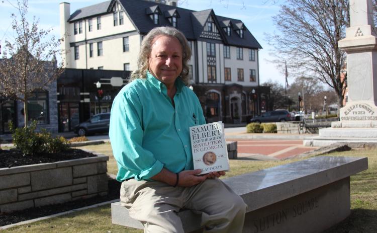 Author Clay Ouzts sits in front of the Samuel Elbert hotel with his book, "Samuel Elbert and the Age of Revolution in Georgia," written about the hotel and county's namesake, Samuel Elbert. (Photo by Wells)