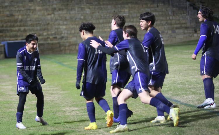 A group of Blue Devils celebrate with teammate Pablo Medellin (left) following the team’s 4-3 overtime win over Rabun County March 14 in the Granite Bowl. The win put the Devils in second place in the region. (Photo by Wells)